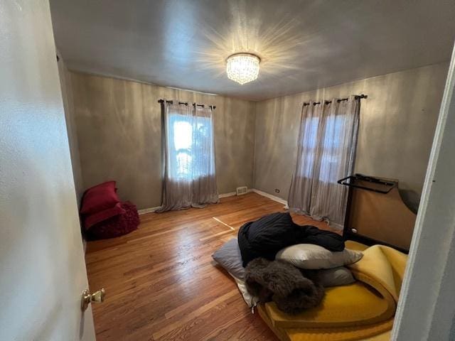 sitting room with wood finished floors, visible vents, and baseboards