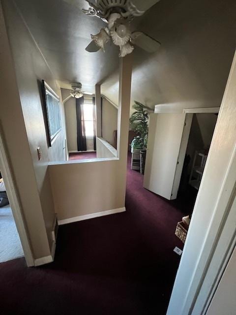 corridor featuring baseboards, carpet floors, and vaulted ceiling