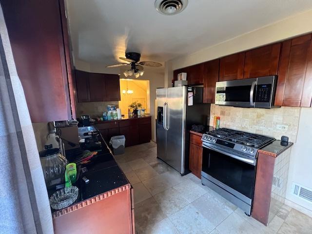 kitchen with dark countertops, backsplash, visible vents, and appliances with stainless steel finishes