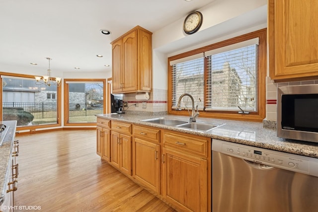 kitchen featuring appliances with stainless steel finishes, a sink, light wood-style floors, backsplash, and recessed lighting