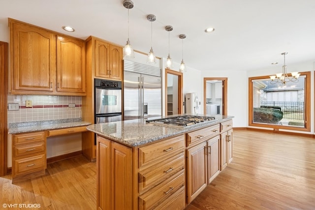 kitchen with pendant lighting, decorative backsplash, appliances with stainless steel finishes, light wood-style floors, and light stone countertops