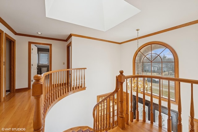 hallway featuring a healthy amount of sunlight, light wood-style floors, a notable chandelier, and an upstairs landing