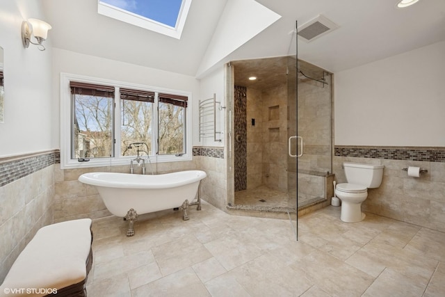 bathroom with visible vents, toilet, a wainscoted wall, and tile walls