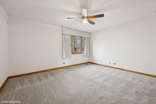 carpeted empty room featuring a ceiling fan, visible vents, and baseboards