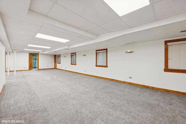 basement with a paneled ceiling, visible vents, light carpet, and baseboards