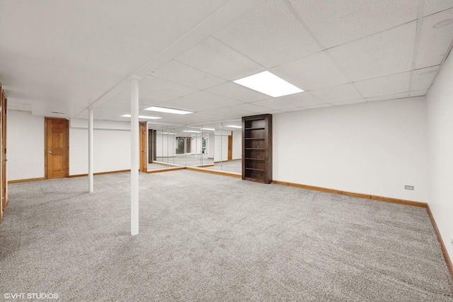 finished basement featuring a paneled ceiling, carpet flooring, and baseboards