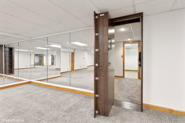 interior space with a paneled ceiling, baseboards, and carpet flooring