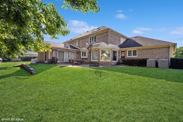 back of property featuring cooling unit, a lawn, a patio, and brick siding