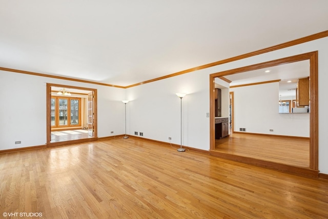 unfurnished living room featuring light wood-style floors, visible vents, ornamental molding, and baseboards