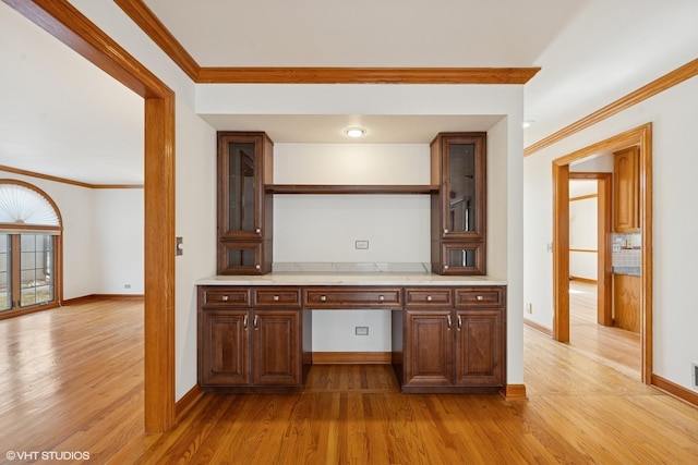 kitchen featuring light wood-style flooring, open shelves, crown molding, and built in study area