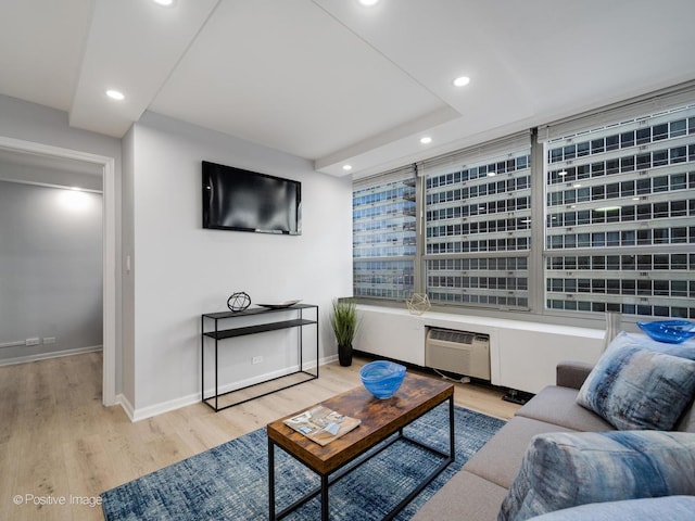 living area featuring light wood-style floors, recessed lighting, a wall unit AC, and baseboards