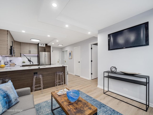 living room with baseboards, light wood-style flooring, and recessed lighting