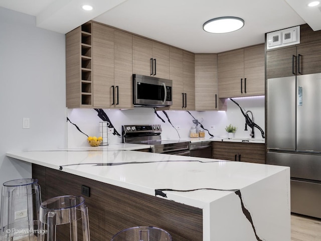 kitchen featuring a peninsula, stainless steel appliances, light countertops, open shelves, and a sink