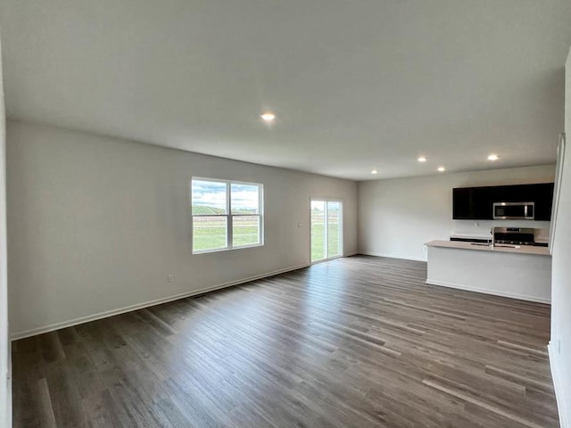 unfurnished living room with dark wood-type flooring, recessed lighting, and baseboards