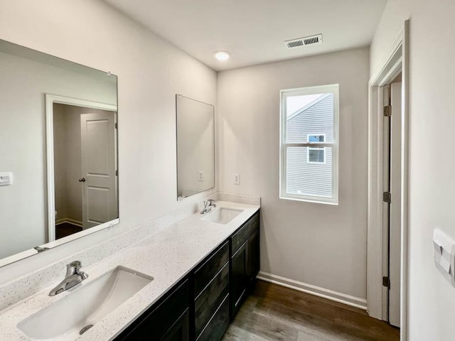 bathroom featuring double vanity, visible vents, a sink, and wood finished floors