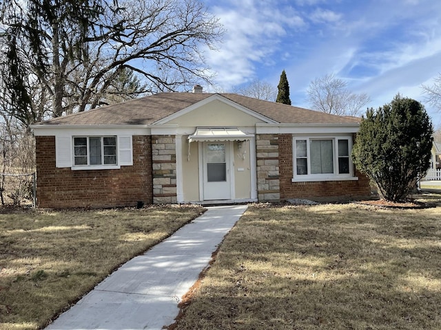 view of front of property with a shingled roof, a front yard, and stone siding