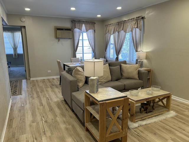 living area with light wood-style floors, crown molding, baseboards, and a wall mounted AC