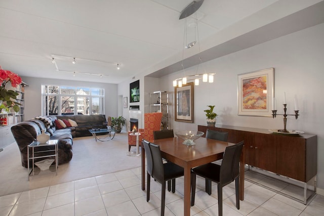 dining space with light tile patterned floors, light carpet, and rail lighting