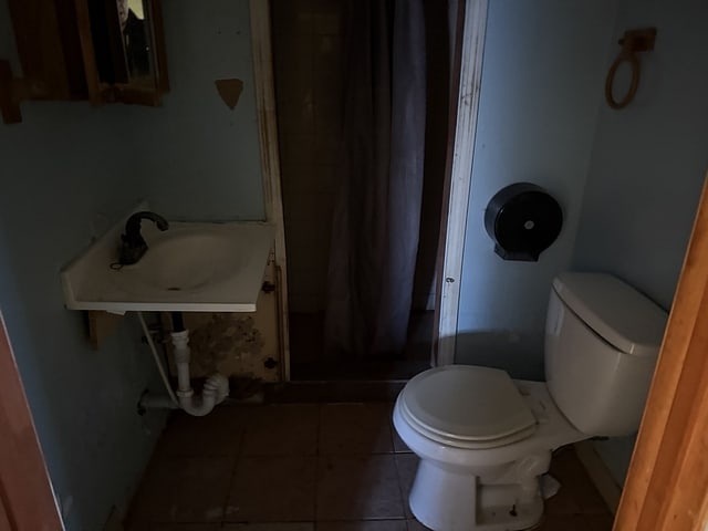 bathroom with tile patterned flooring, a sink, toilet, and a shower stall