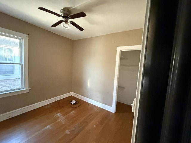 unfurnished bedroom with a closet, ceiling fan, baseboards, and wood finished floors