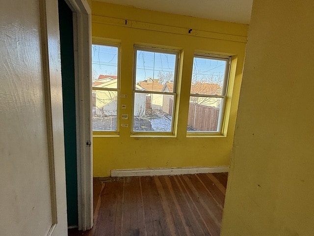 empty room with wood-type flooring and baseboards