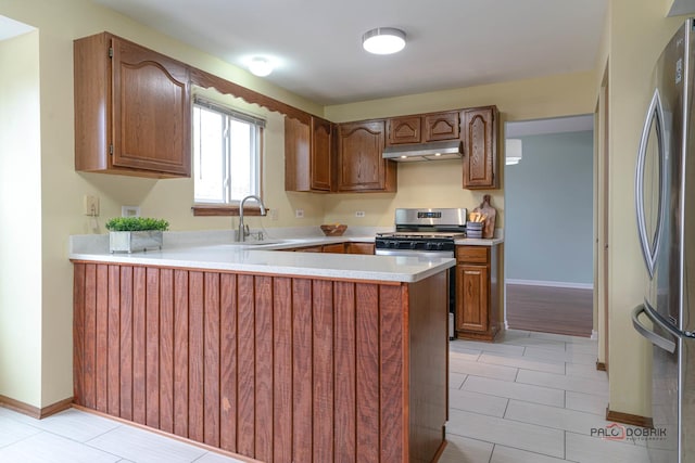 kitchen with under cabinet range hood, stainless steel appliances, a peninsula, a sink, and light countertops