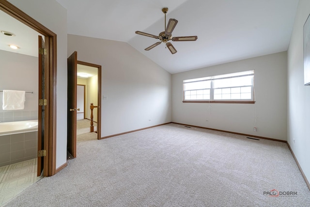 unfurnished bedroom featuring carpet flooring, a ceiling fan, baseboards, vaulted ceiling, and ensuite bath