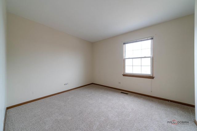 empty room featuring light colored carpet, visible vents, and baseboards