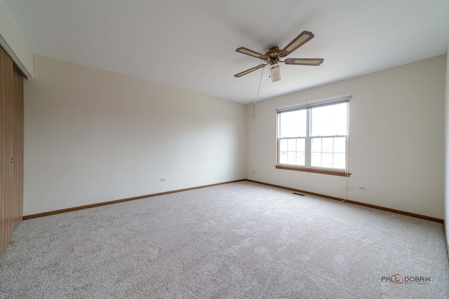 spare room featuring carpet floors, baseboards, visible vents, and a ceiling fan