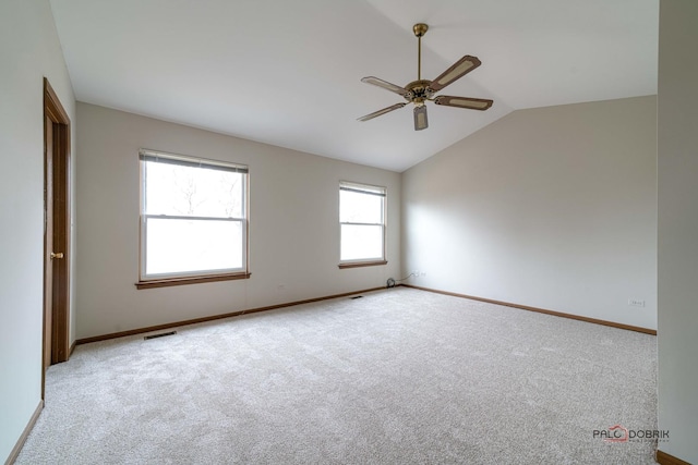 carpeted empty room with a ceiling fan, visible vents, vaulted ceiling, and baseboards