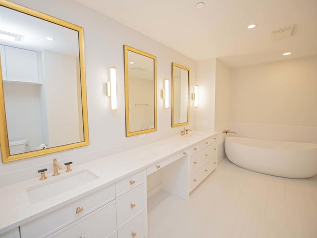 bathroom featuring double vanity, visible vents, a freestanding bath, a sink, and recessed lighting