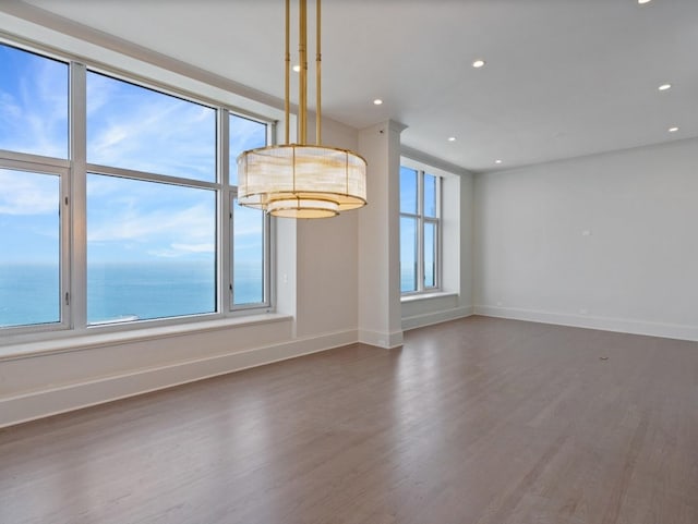 spare room featuring a water view, recessed lighting, wood finished floors, and baseboards