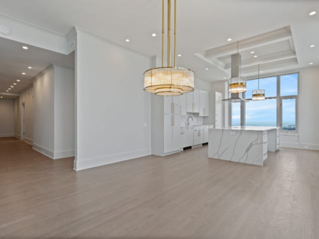 interior space featuring baseboards, a raised ceiling, light wood-style flooring, and recessed lighting