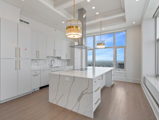 kitchen featuring a center island, light wood-style flooring, extractor fan, white cabinetry, and black electric cooktop