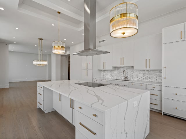 kitchen featuring black electric stovetop, island range hood, a spacious island, wood finished floors, and tasteful backsplash