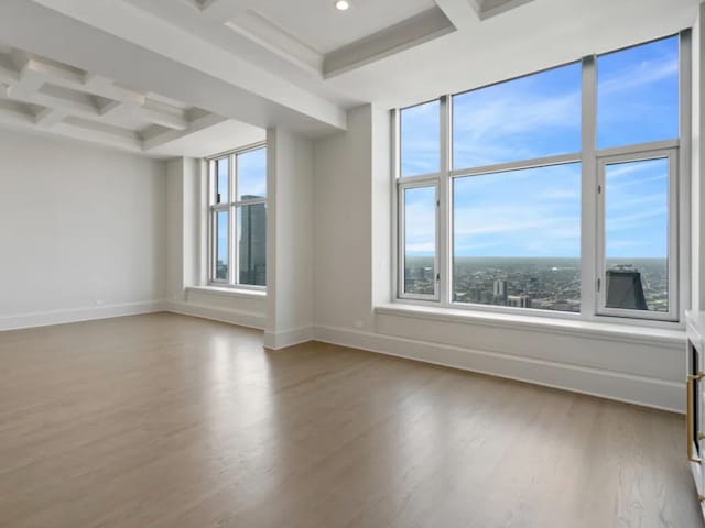 empty room featuring recessed lighting, coffered ceiling, wood finished floors, baseboards, and beamed ceiling