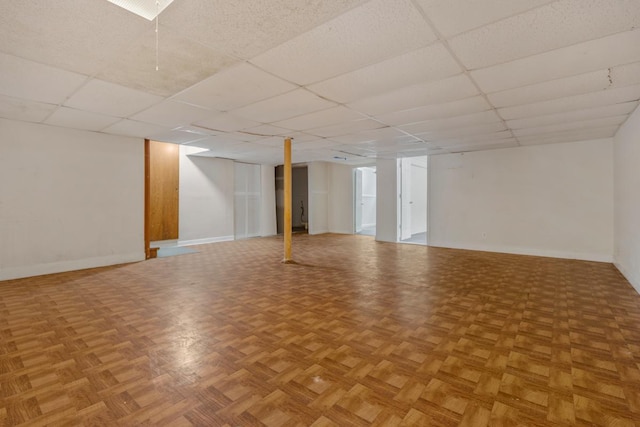 finished below grade area featuring a drop ceiling and baseboards