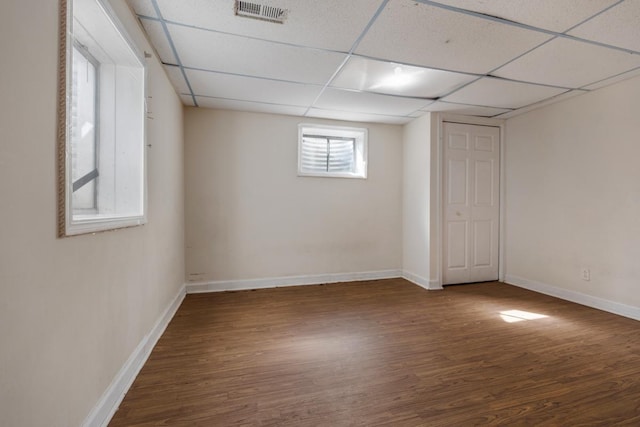 below grade area with a paneled ceiling, visible vents, baseboards, and wood finished floors