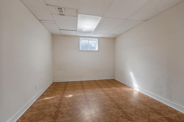 basement with baseboards, visible vents, and a drop ceiling