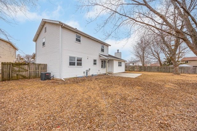 rear view of property with a patio area, a fenced backyard, a chimney, and central AC unit