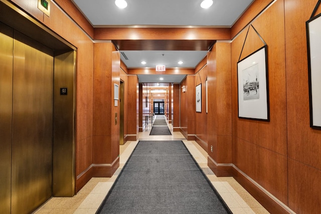 corridor featuring elevator, wooden walls, baseboards, and recessed lighting