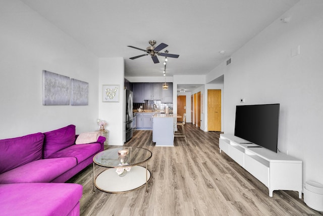 living room with light wood-style floors, visible vents, and a ceiling fan