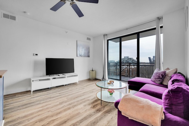 living area with baseboards, ceiling fan, visible vents, and wood finished floors