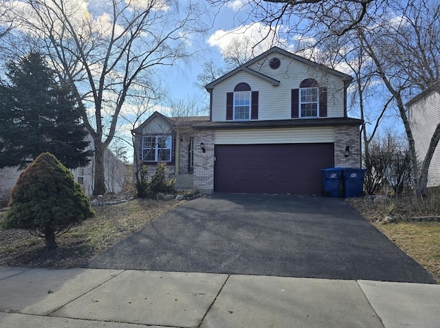 tri-level home featuring a garage, brick siding, and aphalt driveway