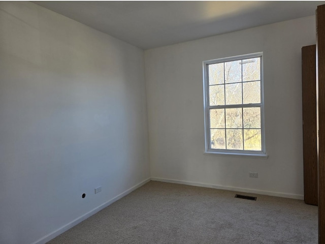 spare room with baseboards, visible vents, and light colored carpet