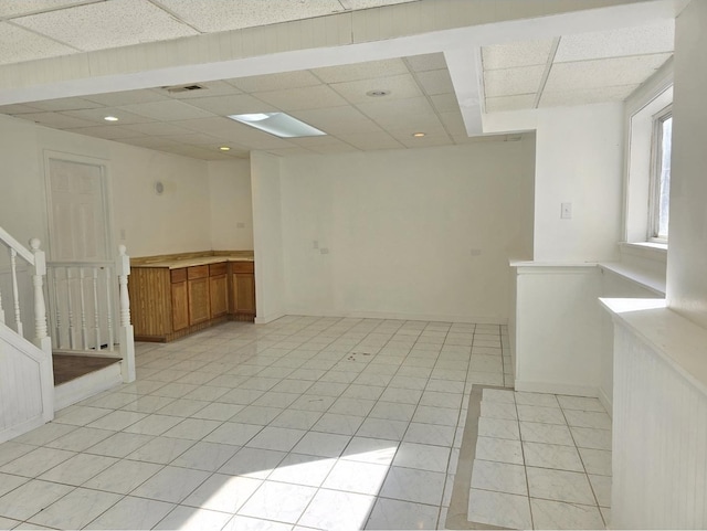 empty room with baseboards, visible vents, a drop ceiling, stairway, and light tile patterned flooring