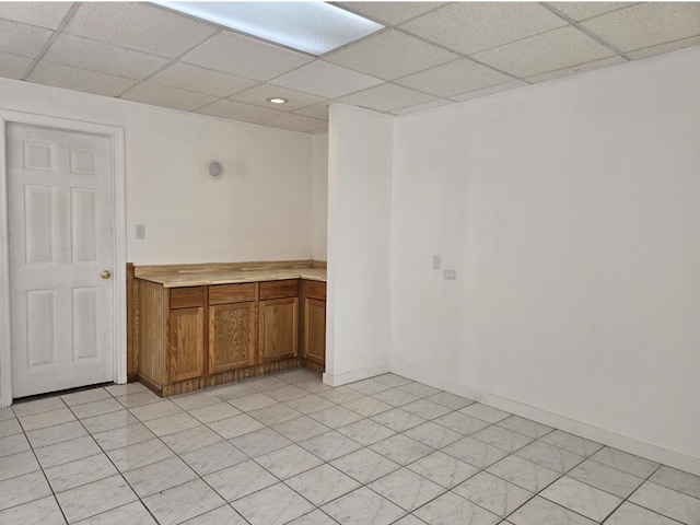 interior space with a drop ceiling and baseboards