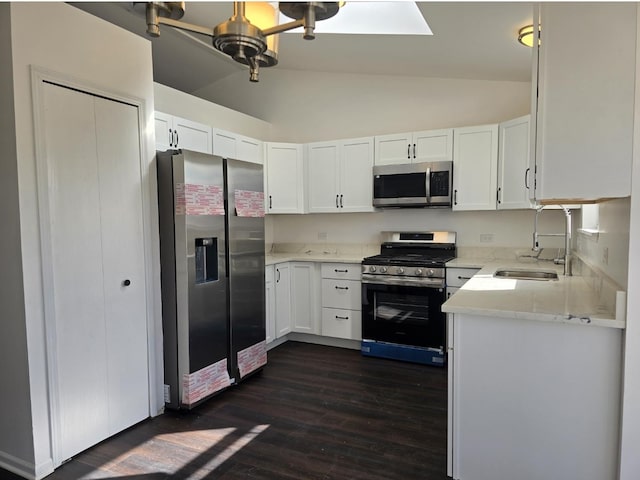 kitchen featuring white cabinets, lofted ceiling with skylight, dark wood-style floors, stainless steel appliances, and a sink