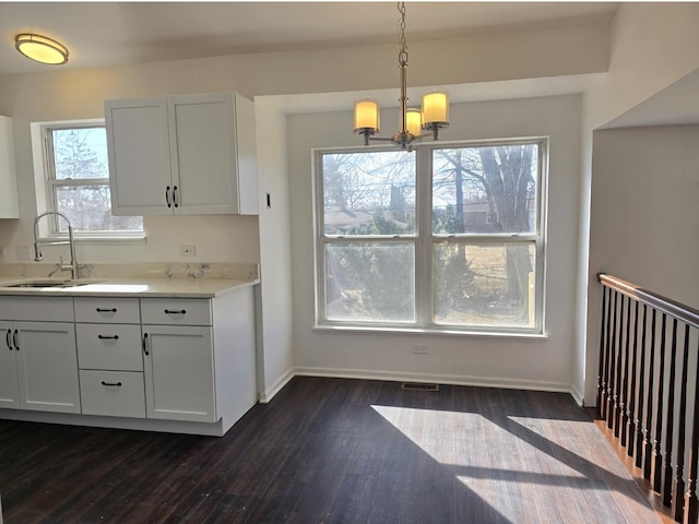 kitchen with baseboards, dark wood-style floors, light countertops, pendant lighting, and a sink