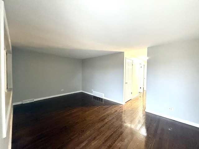 spare room with visible vents, dark wood-style flooring, and baseboards